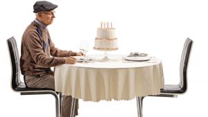 An elderly man sitting alone at a table.