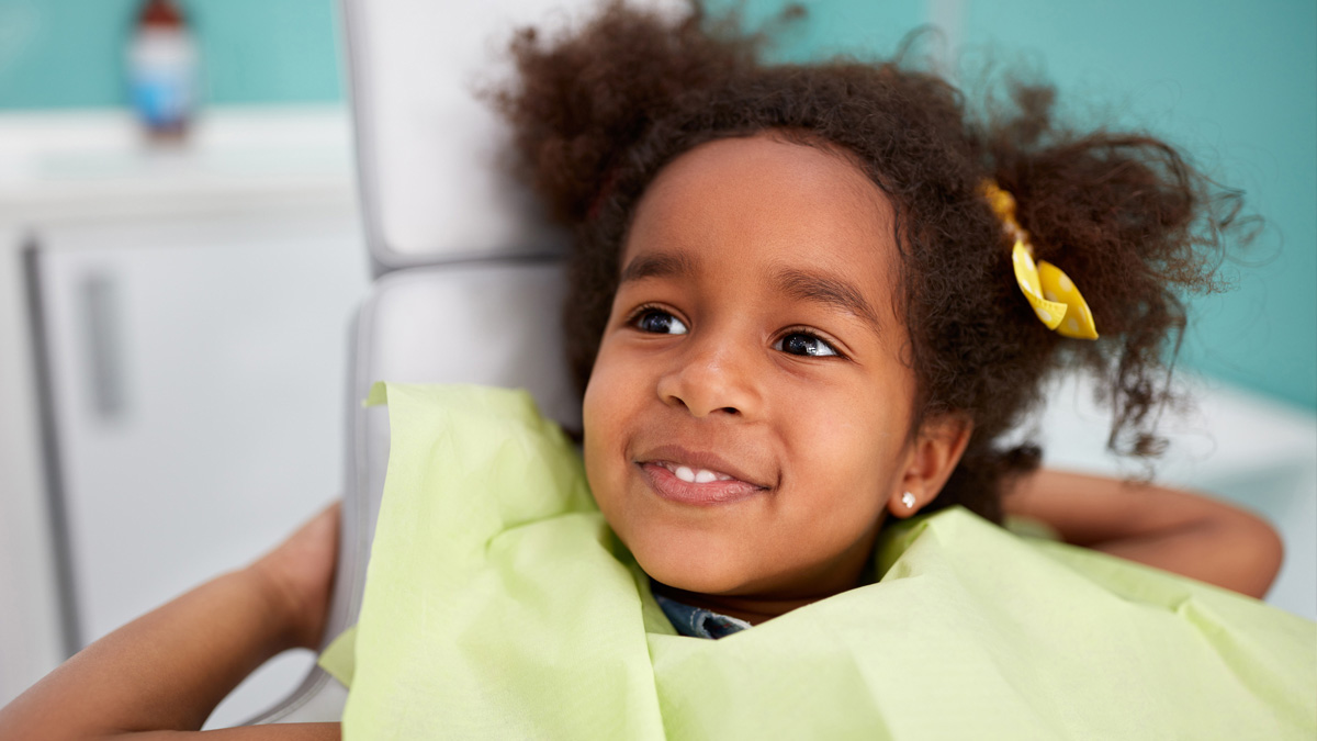 Young girl sitting in dental chair smiling