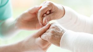 Staff at Pruitt Hospice holds the hands of a senior