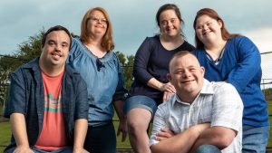 Five smiling faces - living with Down Syndrome.