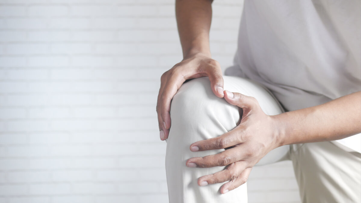 A person holding their knee with joint pain