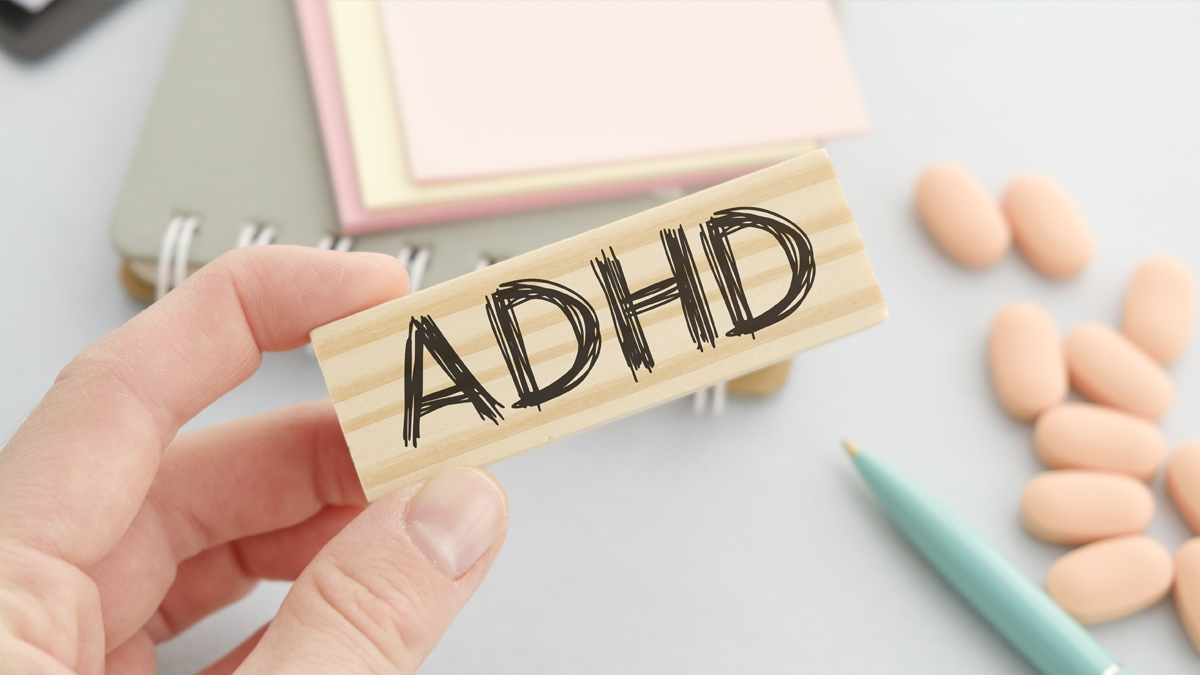 photo of a hand holding a wooden sign with ADHD on it
