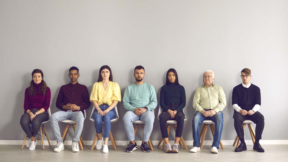 Photo of men and women sitting against a wall