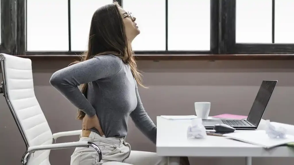 A woman using a laptop computer with back pain